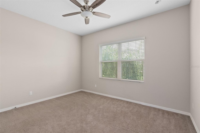 carpeted empty room with baseboards and a ceiling fan