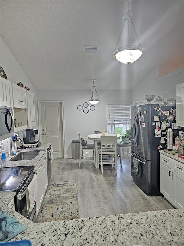 kitchen with lofted ceiling, stainless steel appliances, white cabinetry, and sink