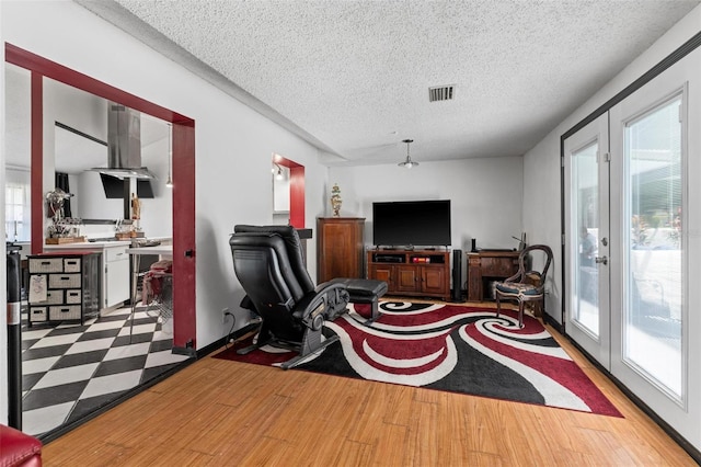 interior space with french doors, light wood-type flooring, and a textured ceiling