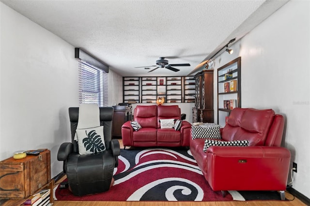 living room featuring ceiling fan, wood-type flooring, and a textured ceiling