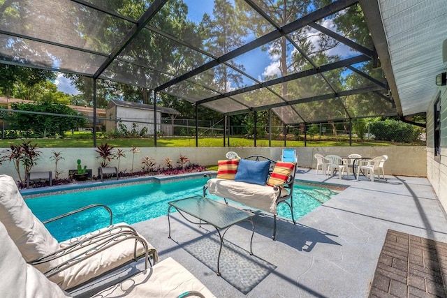 view of swimming pool featuring a patio, a yard, a storage unit, and a lanai