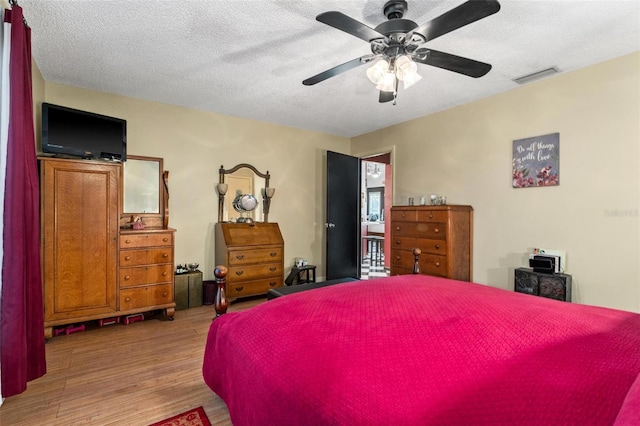 bedroom featuring ceiling fan, a textured ceiling, and light hardwood / wood-style flooring