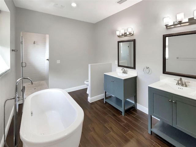 bathroom featuring vanity, toilet, wood-type flooring, and a washtub