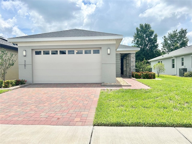 view of front of property with cooling unit, a front yard, and a garage