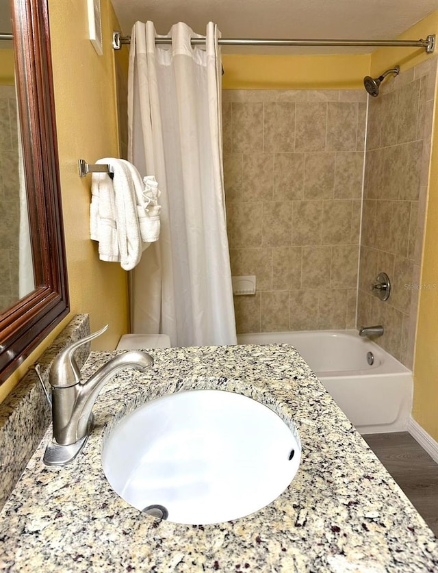 bathroom with wood finished floors, a sink, and shower / tub combo with curtain