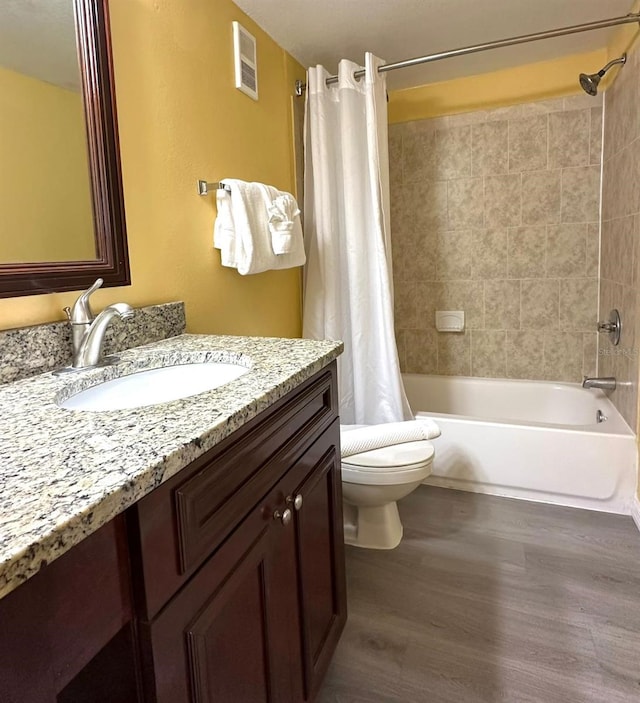 bathroom with visible vents, toilet, shower / bath combo, vanity, and wood finished floors