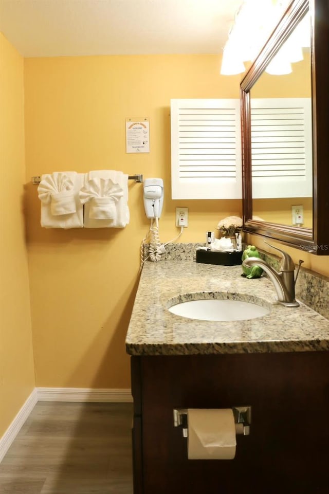 bathroom with wood finished floors, vanity, and baseboards