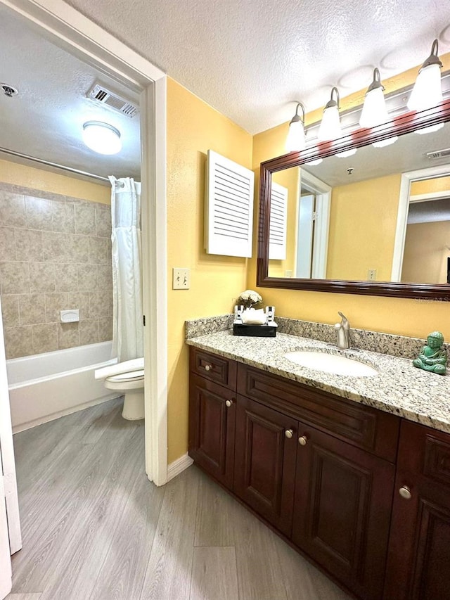 full bath with visible vents, toilet, wood finished floors, a textured ceiling, and vanity