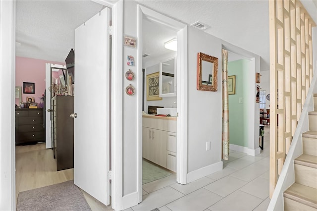 hall featuring light tile patterned floors and a textured ceiling