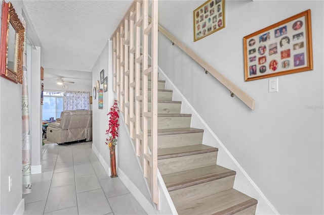 stairway featuring tile patterned floors, ceiling fan, and a textured ceiling