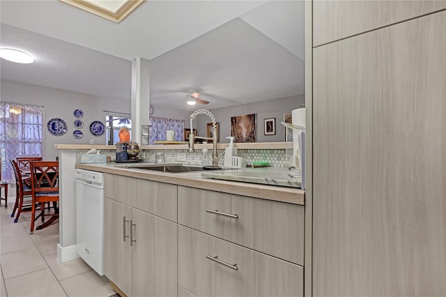 kitchen featuring tasteful backsplash, dishwasher, kitchen peninsula, sink, and light tile patterned flooring