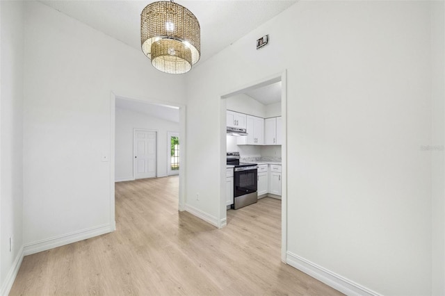 hall featuring light hardwood / wood-style floors, vaulted ceiling, and a chandelier