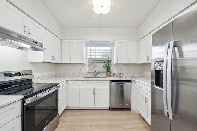 kitchen featuring sink, light hardwood / wood-style floors, a textured ceiling, white cabinets, and appliances with stainless steel finishes