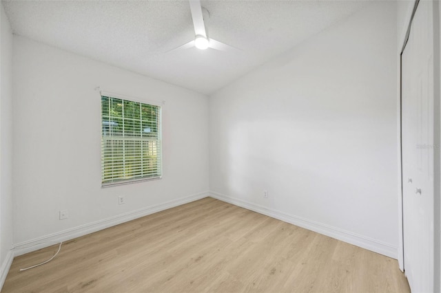 empty room with a textured ceiling and light hardwood / wood-style flooring