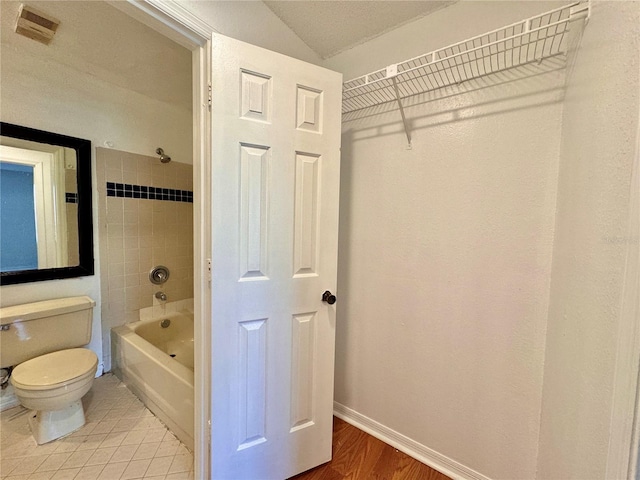 bathroom featuring toilet, tiled shower / bath combo, and wood-type flooring