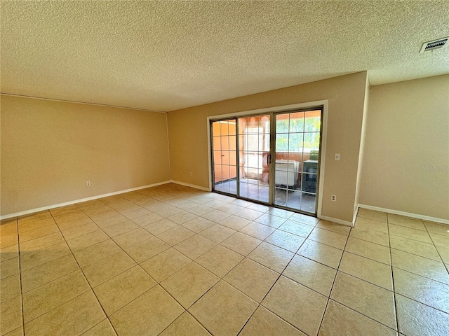 spare room with light tile patterned floors and a textured ceiling