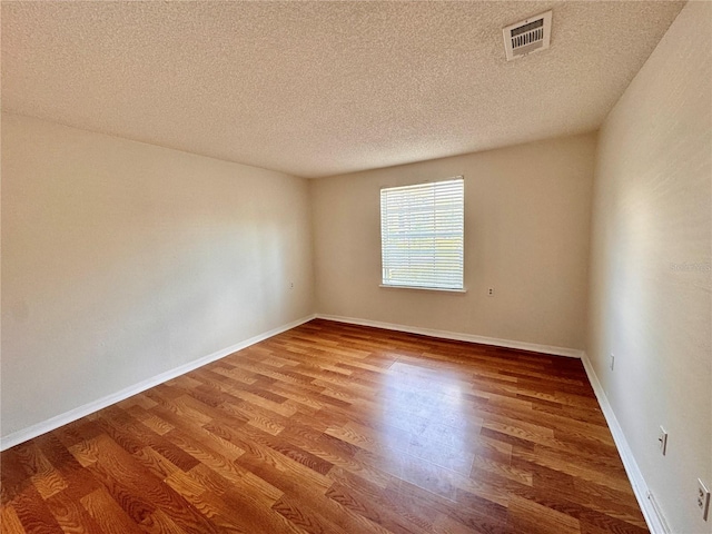 spare room featuring hardwood / wood-style floors and a textured ceiling