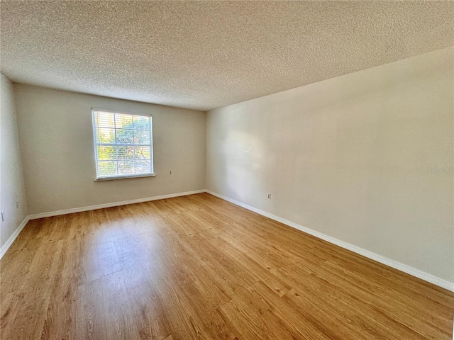 empty room with wood-type flooring and a textured ceiling