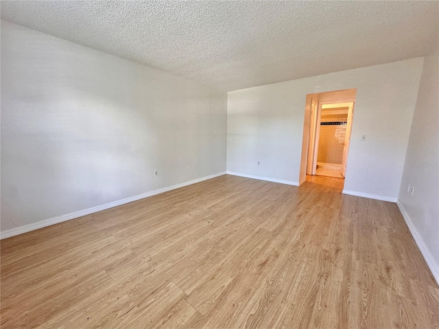 unfurnished room with a textured ceiling and light hardwood / wood-style floors