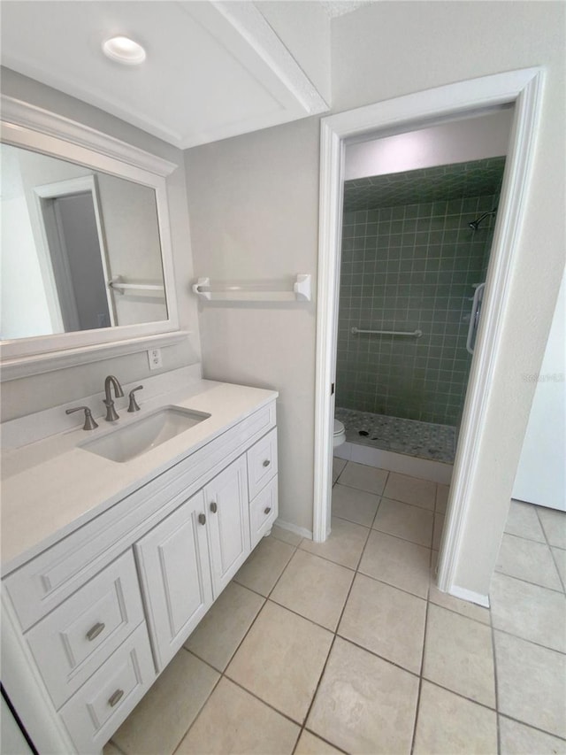 bathroom with vanity, toilet, tiled shower, and tile patterned floors