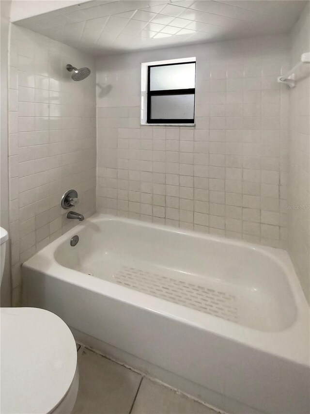 bathroom featuring toilet, tile patterned floors, and tiled shower / bath