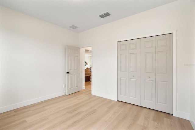 unfurnished bedroom featuring light hardwood / wood-style flooring and a closet