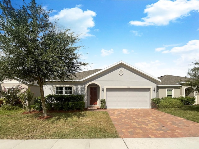 ranch-style home with a front lawn, decorative driveway, an attached garage, and stucco siding