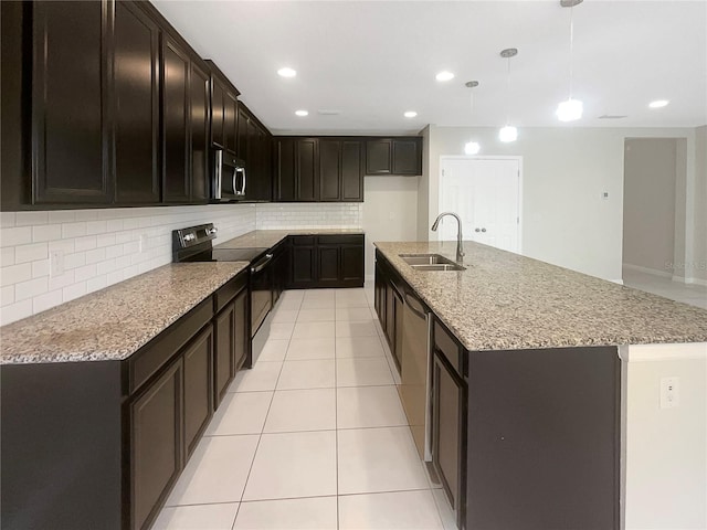 kitchen featuring stainless steel appliances, light tile patterned flooring, a sink, and light stone countertops