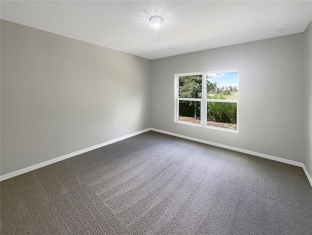 empty room featuring dark carpet and baseboards