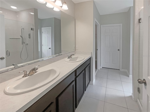 bathroom with double vanity, tiled shower, a sink, and tile patterned floors