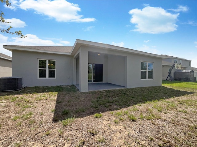 back of property with a patio area, central AC unit, a lawn, and stucco siding