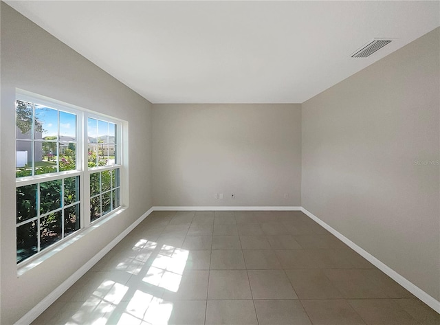 tiled spare room featuring visible vents and baseboards