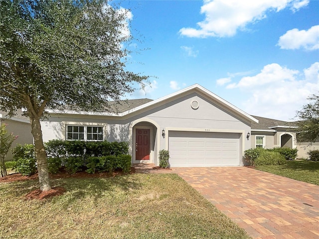 ranch-style house with a garage, a front lawn, decorative driveway, and stucco siding