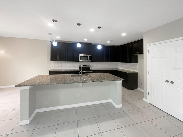 kitchen featuring appliances with stainless steel finishes, tasteful backsplash, a sink, and light stone countertops