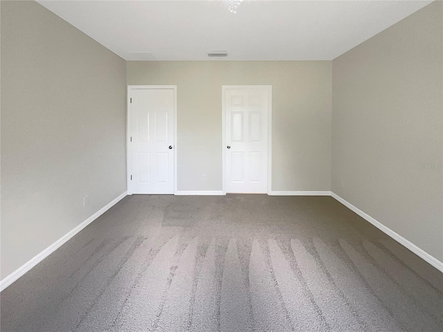 unfurnished bedroom with carpet flooring, visible vents, and baseboards