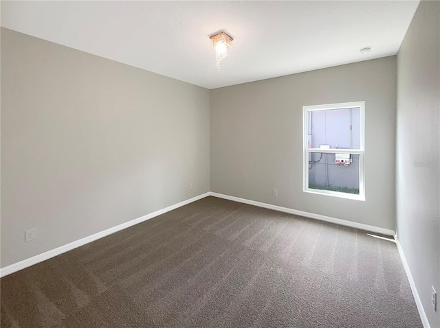 empty room featuring dark carpet and baseboards