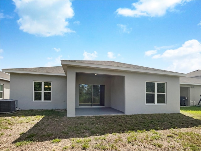 back of property with a yard, central AC, and stucco siding