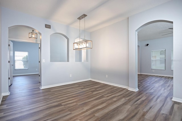 empty room featuring a textured ceiling, dark hardwood / wood-style floors, and ceiling fan with notable chandelier