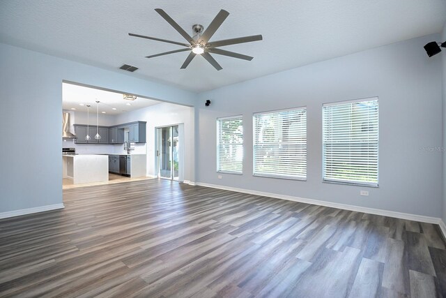 unfurnished living room with dark hardwood / wood-style flooring, ceiling fan, and a textured ceiling