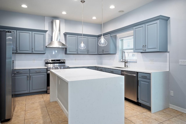 kitchen with decorative light fixtures, stainless steel appliances, sink, wall chimney exhaust hood, and a kitchen island