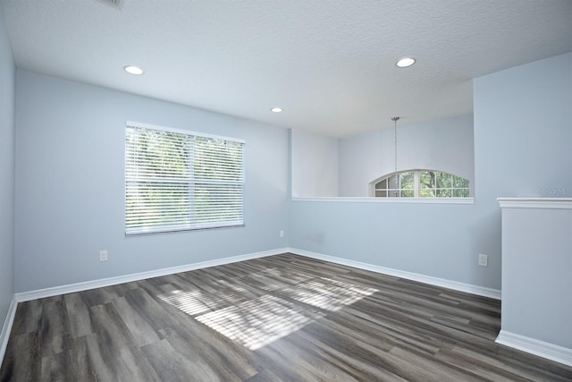 spare room featuring a textured ceiling and dark hardwood / wood-style floors