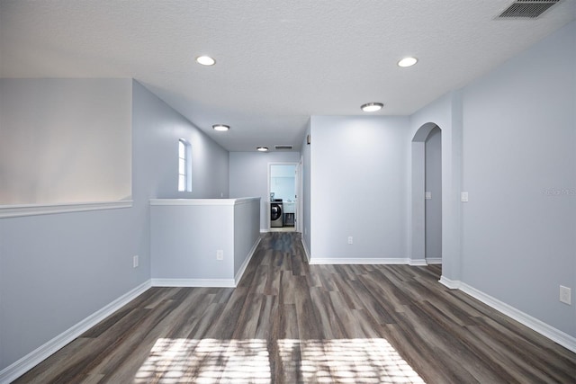 empty room featuring baseboards, wood finished floors, visible vents, and arched walkways