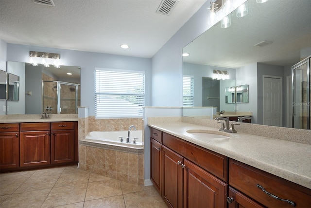 bathroom with visible vents, a garden tub, two vanities, a sink, and a shower stall