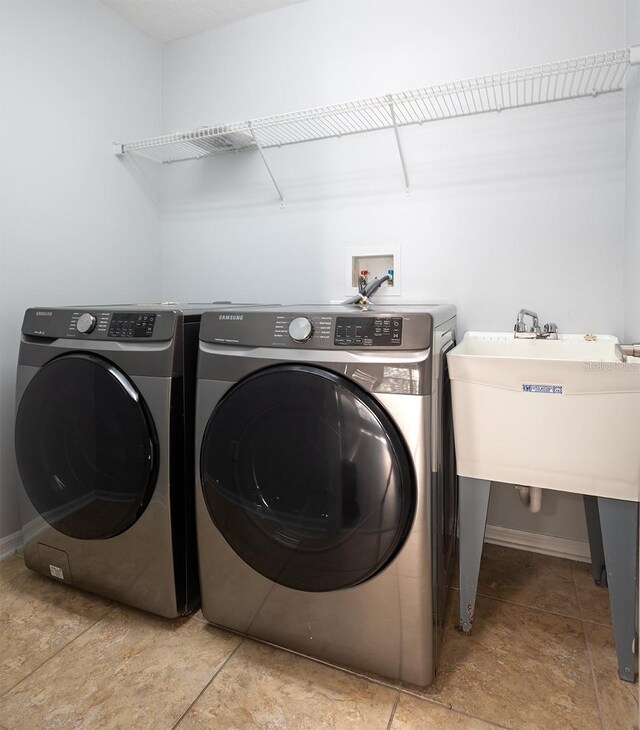 clothes washing area with independent washer and dryer and light tile patterned flooring