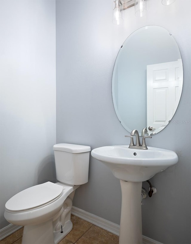 bathroom with toilet, sink, and tile patterned floors