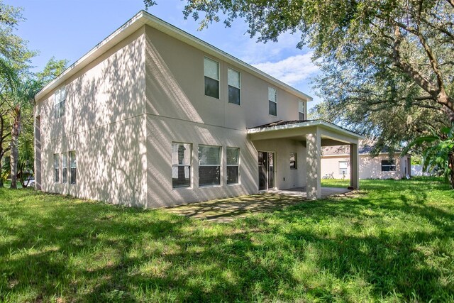 rear view of property featuring a lawn and a patio