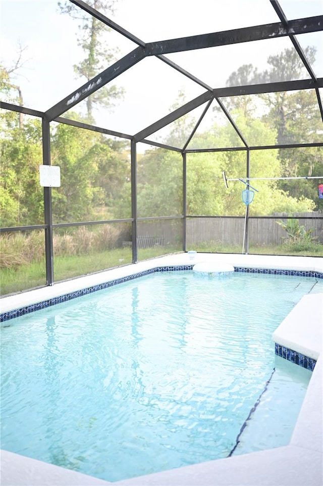 view of swimming pool featuring glass enclosure