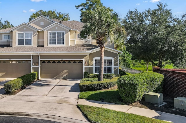 view of front of house with stucco siding, a shingled roof, an attached garage, fence, and driveway