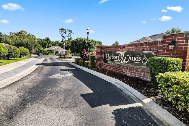 view of road with street lights, a gate, sidewalks, a gated entry, and curbs