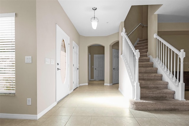 entrance foyer with arched walkways, light tile patterned flooring, and baseboards